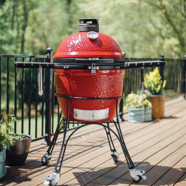 Shelves in place on a Classic Joe II grill outside on the porch. Hooks on shelves hold grill gripper and ash tool.