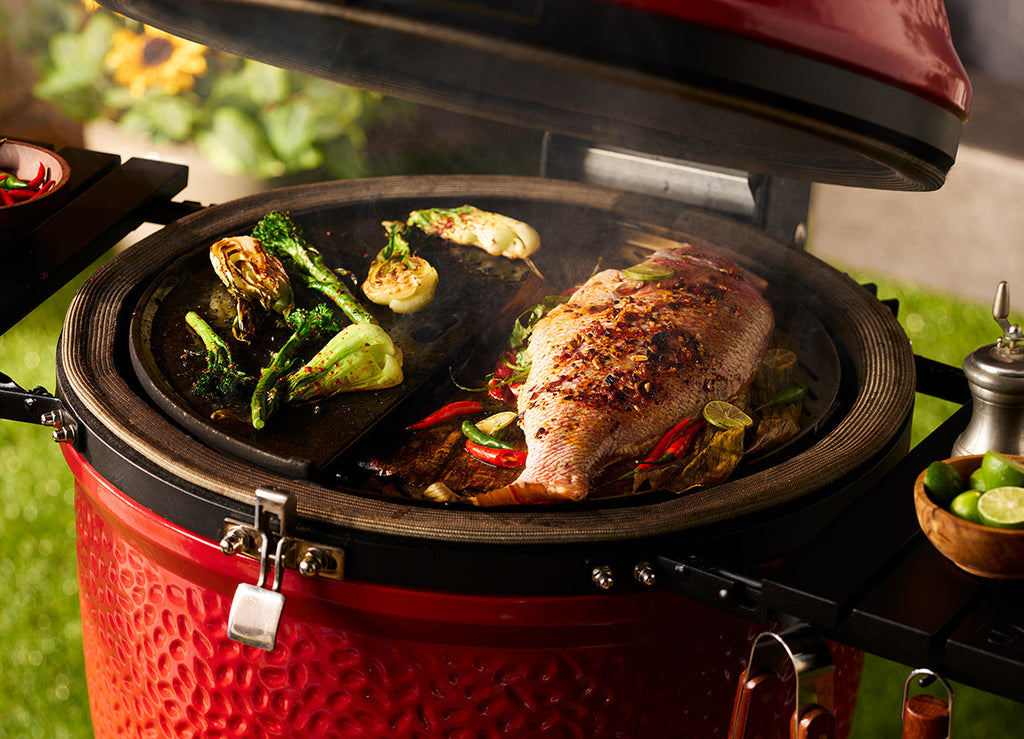 Vegetables and a whole fish cook on 2 half-moon cooking surfaces