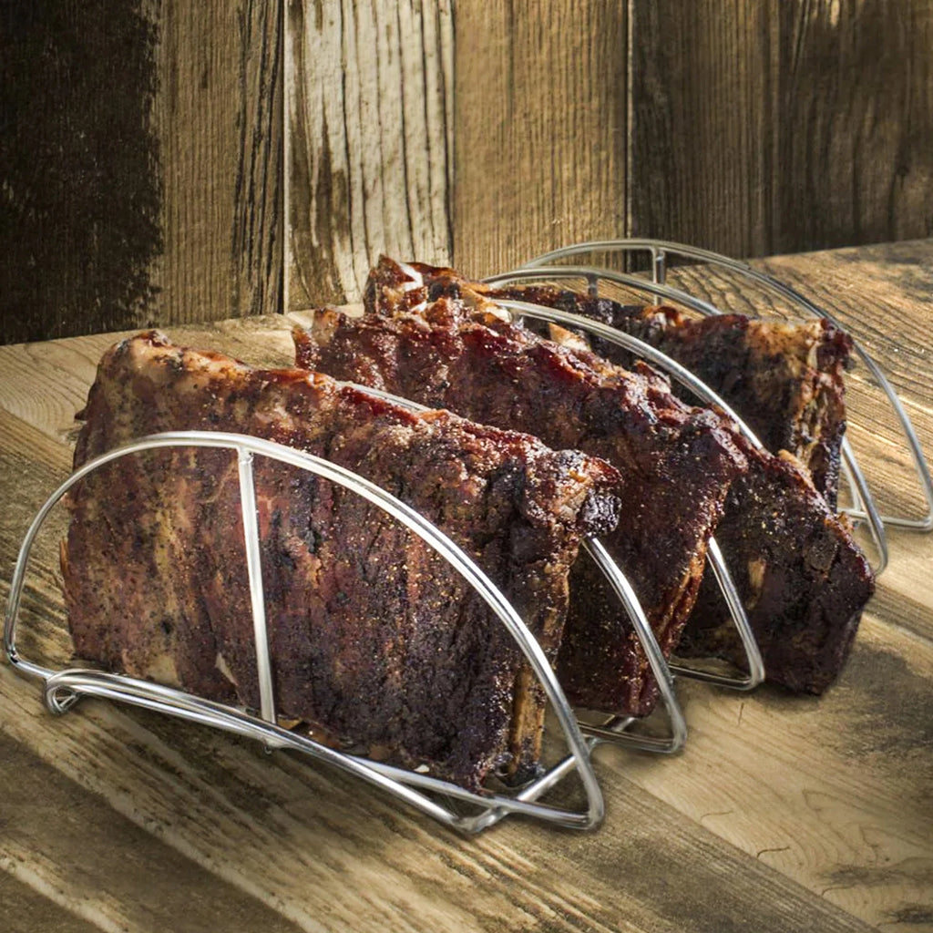 Barbecued ribs standing vertically in a stainless steel rib rack with a wooden background