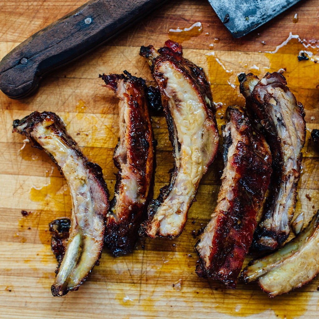 Sliced ribs on a wooden cutting board with a knife in the background