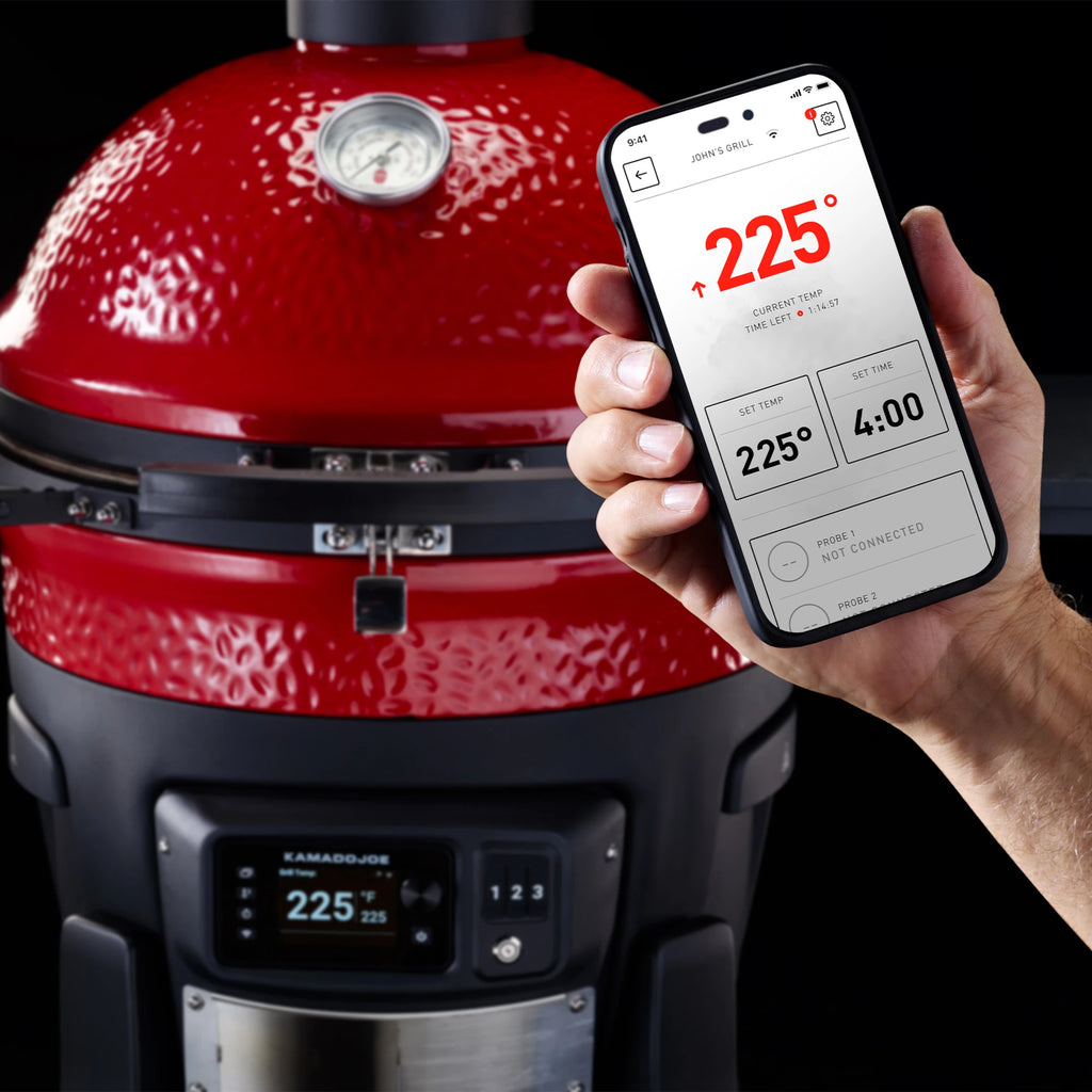 A hand holding a smart phone with the Kamado Joe app running in front of a Konnected Joe Grill. The app and the Kontrol Panel both show the grill is 225°