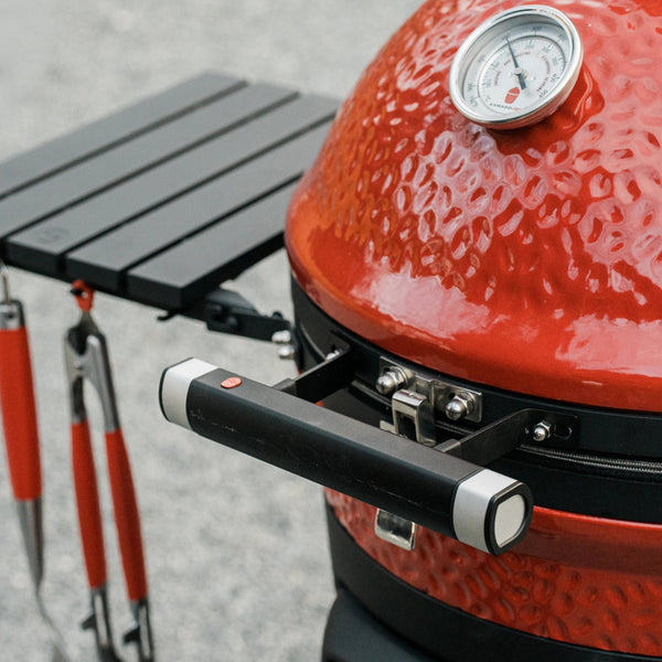 A closed Kamado Joe grill with the LED Handle installed in place of the original handle. The handle brackets are shaped to mount snugly against the curve of the grill.