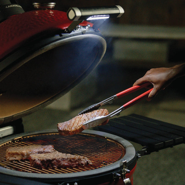The LED Handle in use. The handle is mounted on the grill and the grill is open to show how the light shines onto the cooking surface once the lid is lifted.