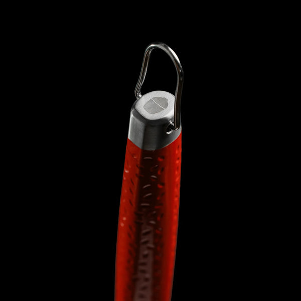 Closeup of the end of the handle of a Kamado Joe spatula showing the dimpled red surface, the convenient handing hook, and the Kamado Joe grill logo etched into the end of the handle.