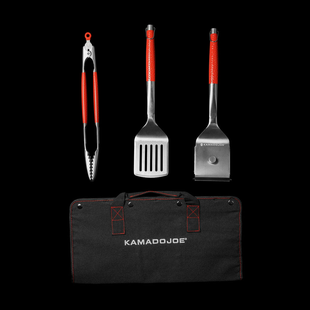 Kamado Joe tongs, spatula, and grill brush above a folded black canvas carrying case with red accent stitching and the words Kamado Joe in white.