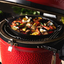 Mussels, shrimp and lemons cook in a paella pan inside a Kamado Joe grill