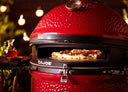 A pizza cooks in a DoJoe installed in a Kamado Joe grill